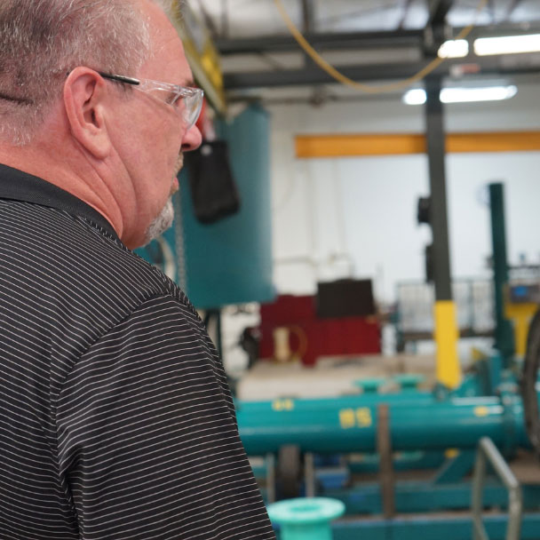 A man looking at industrial scene with green pipelines.