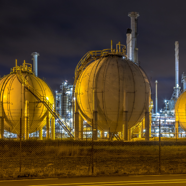 LNG and CNG: Round liquid natural gas containers illuminated at nighttime.